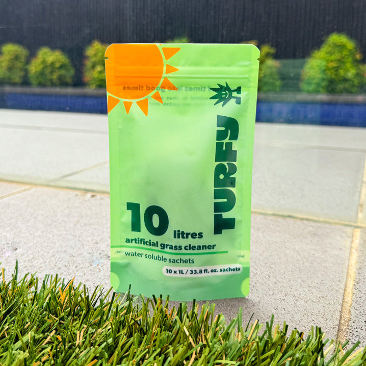 A Turfy probiotic cleaning pack shown in a sunny backyard, ready to be dissolved and sprayed on artificial grass.
